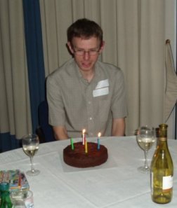 Picture of Paul behind a table with a chocolate cake and a couple of wine glasses Picture of Paul behind a table with a chocolate cake and a couple of wine glasses